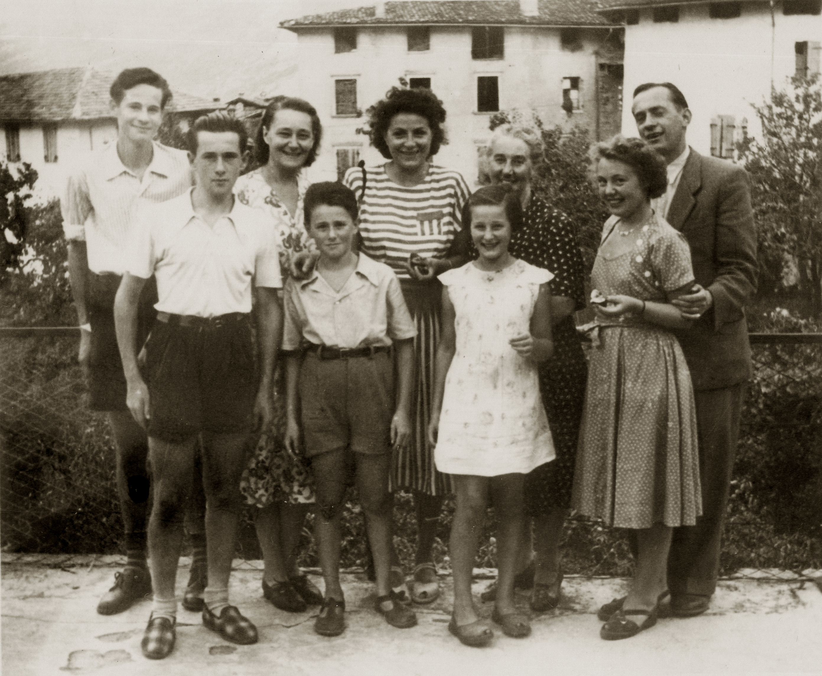 A photo of nine people - three men, four women, one boy and one girl. The photo is sepia toned and shows the owners' family in Italy.