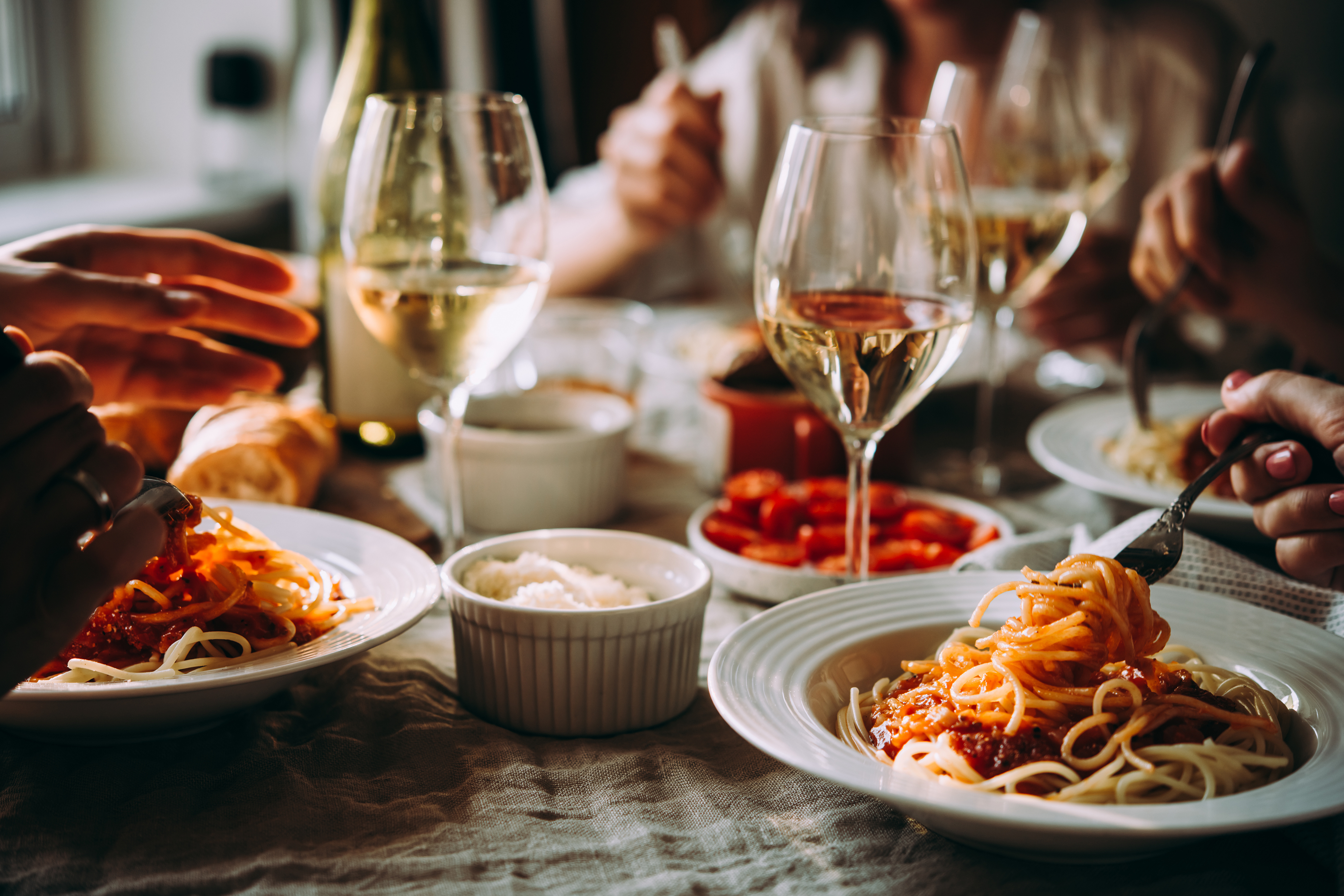 Glasses of wine on a table with small plates and bowls of pasta